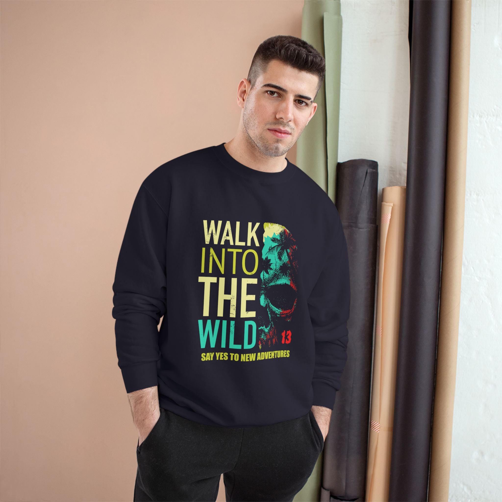Man wearing a black sweatshirt with a colorful graphic and text, standing indoors.