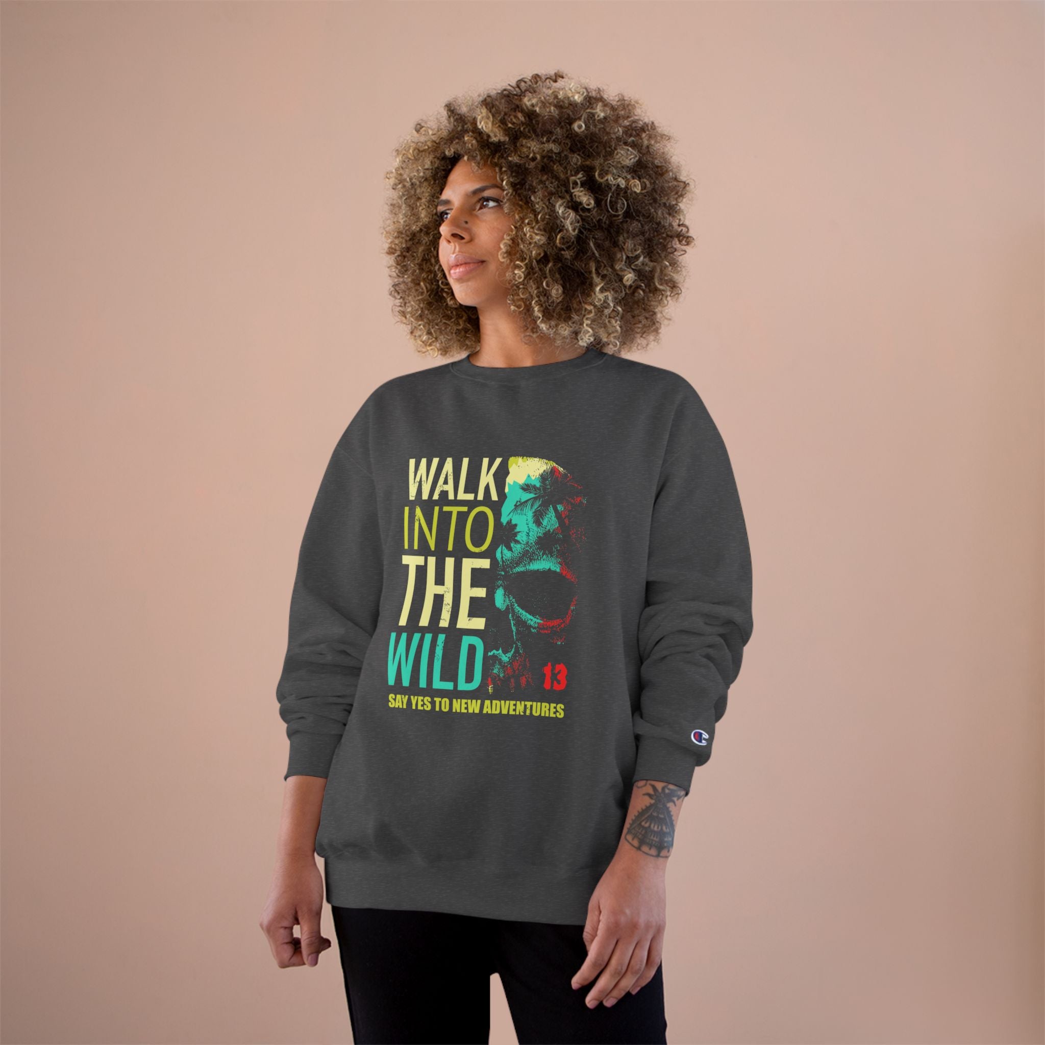 Person wearing a dark gray sweatshirt with 'Walk into the Wild' text and graphic on a beige background
