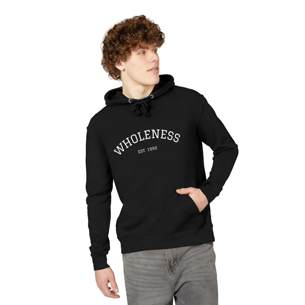 Person wearing a black hoodie with 'WHOLENESS EST. 1985' text on a white background