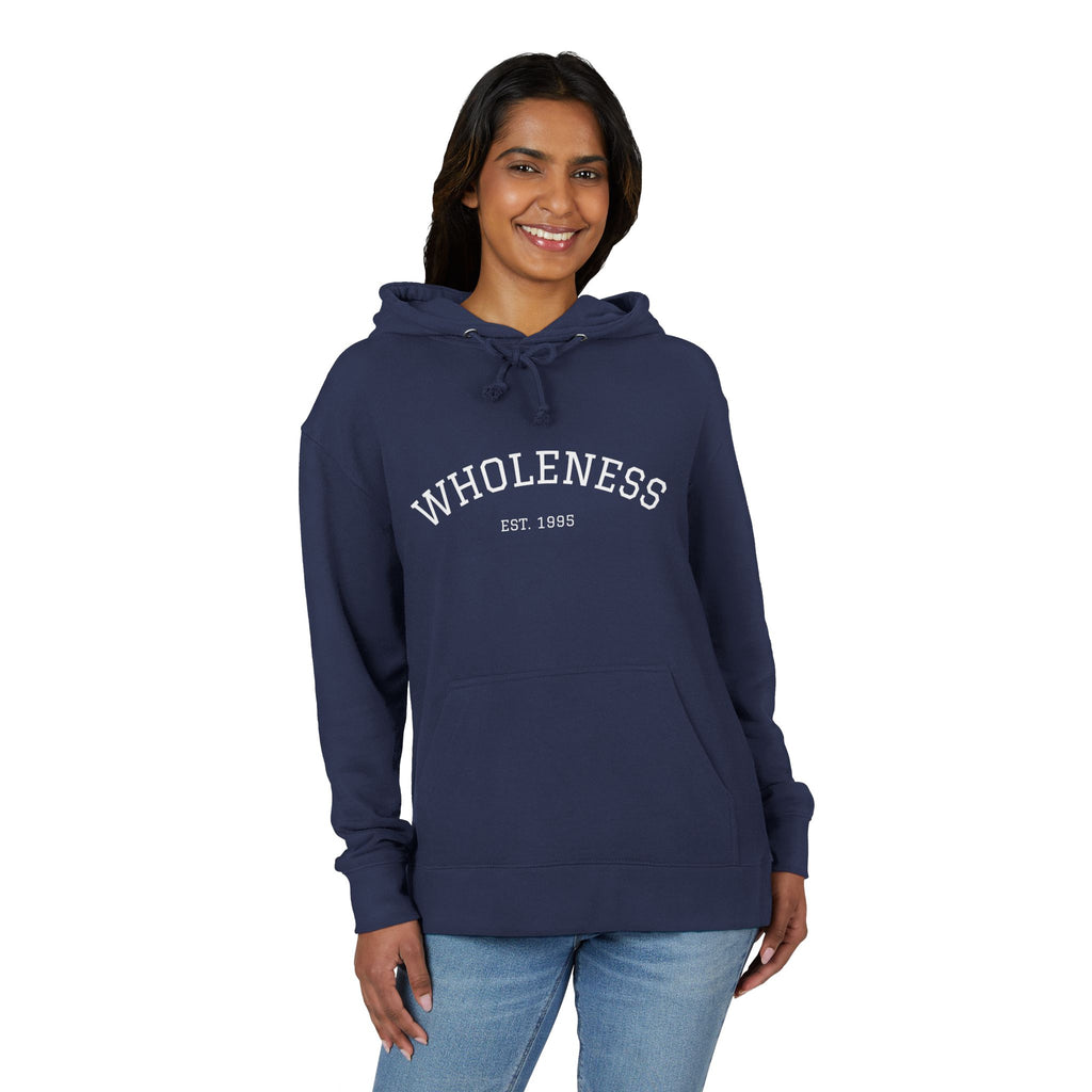 Person wearing a navy hoodie with 'WHOLENESS EST. 1985' text on a white background